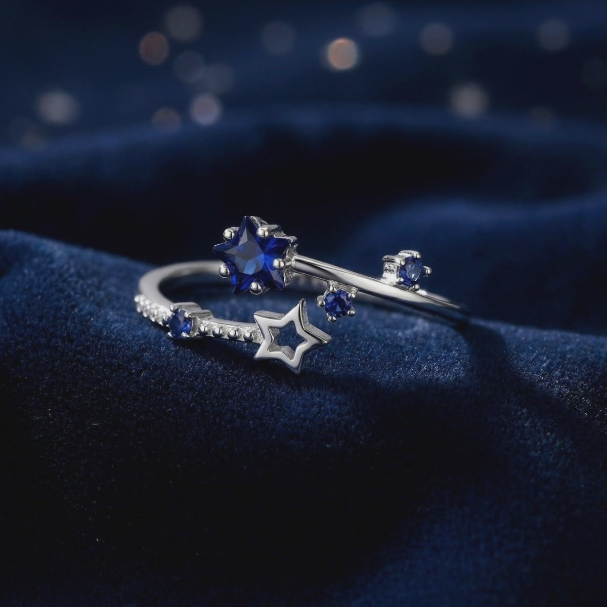 A detailed view of The Orionis Star Ring, a solid gold ring showcasing royal blue simulated sapphires in a bypass setting.