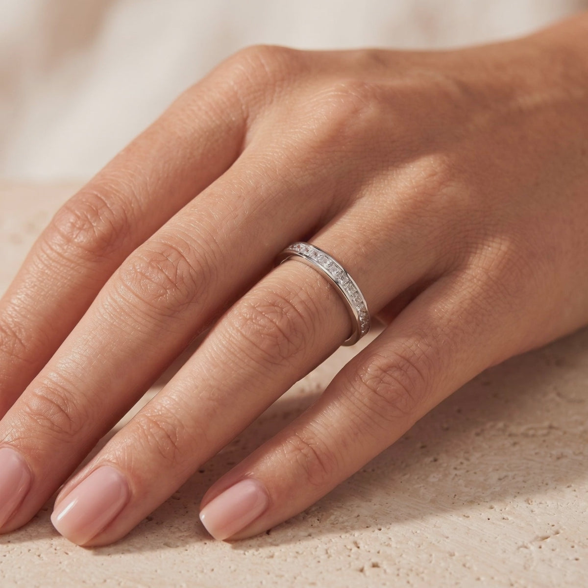 Silver channel-set eternity ring with princess-cut cubic zirconia worn on a hand