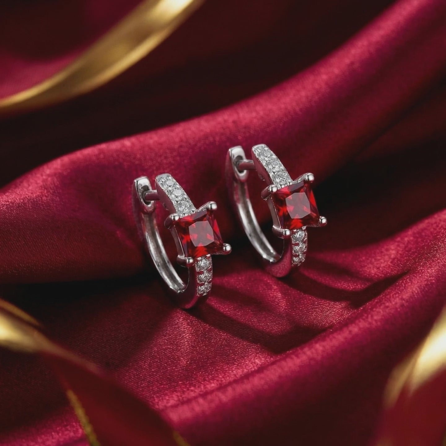 Square huggie earrings in solid gold with simulated rubies.