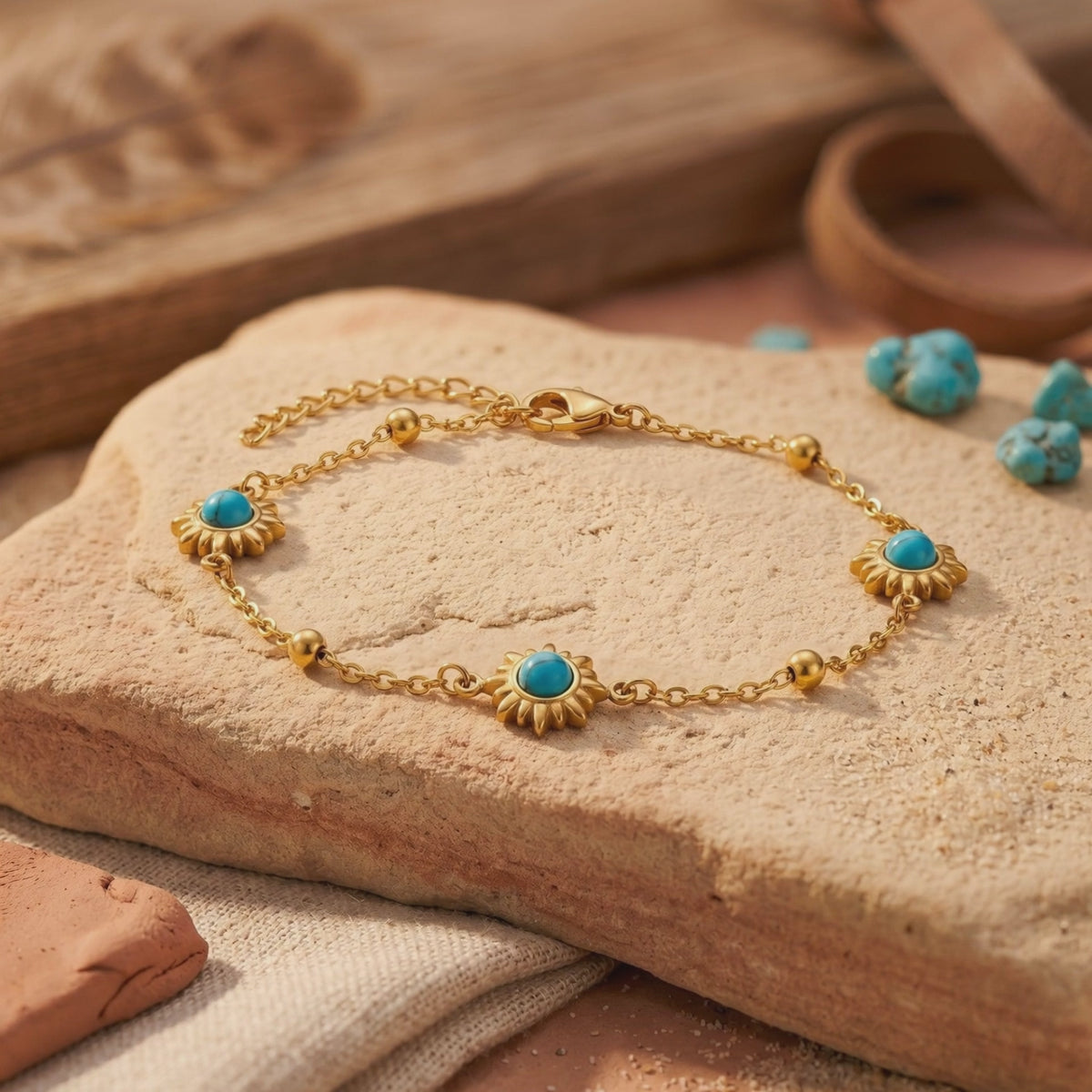 Gold-tone station bracelet with sunburst turquoise-colored stones displayed on a textured stone slab.