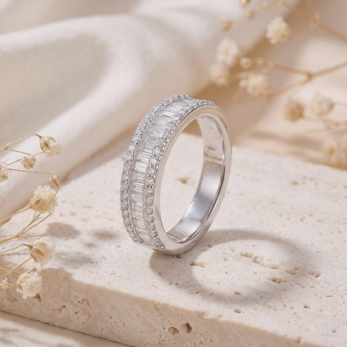 Silver baguette and micro-pavé cubic zirconia band standing upright on a textured beige stone block.