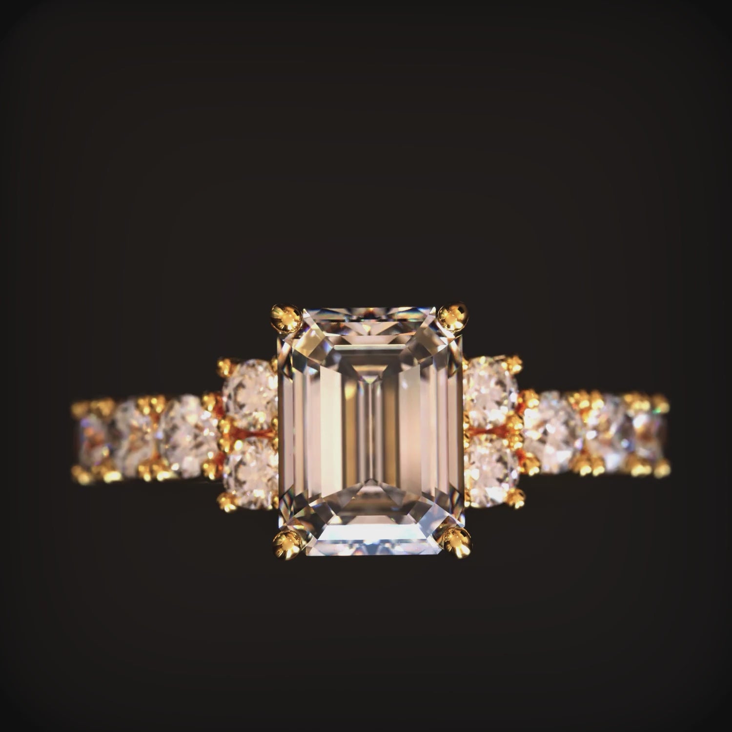 A solid gold ring with an emerald-cut moissanite center stone.