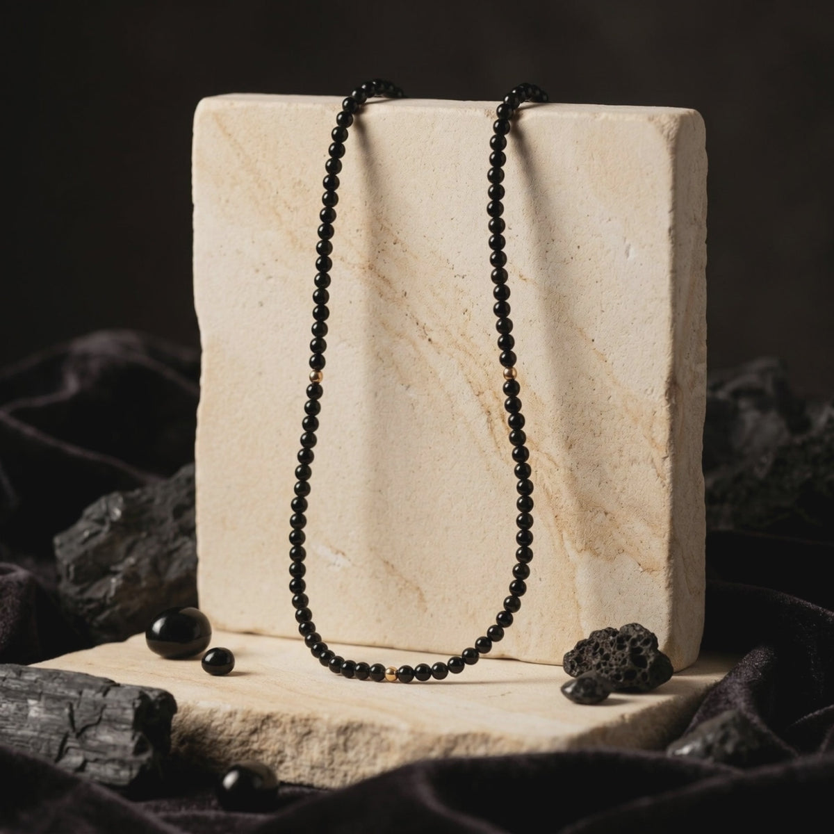A solid gold necklace with natural black onyx beads.
