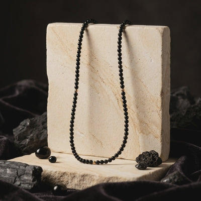 A solid gold necklace with natural black onyx beads.