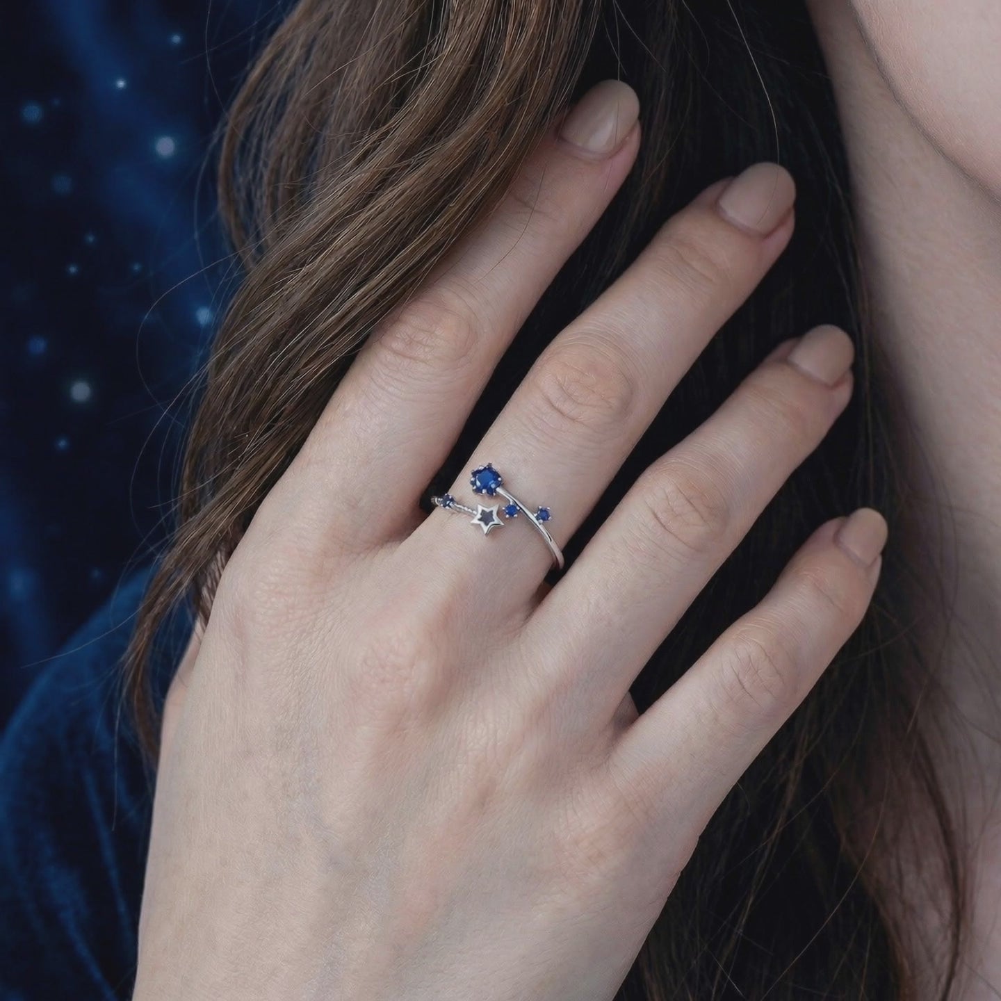 The Orionis Star Ring, a solid gold ring featuring precision-cut simulated sapphire stones in a star-themed bypass design.