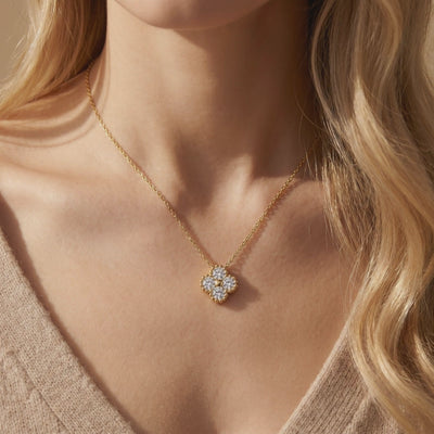 Gold-toned clover moissanite pendant necklace worn on a model's upper chest.