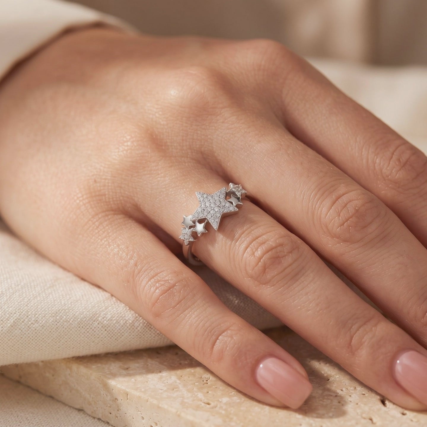 Silver star cluster ring worn on a finger, featuring a pavé-set central star and smaller star accents.