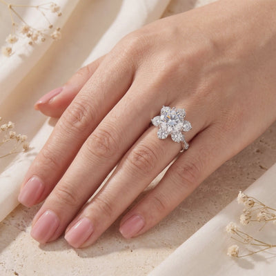 The silver Roselita ring worn on a hand, featuring a round center stone in a flower halo setting.