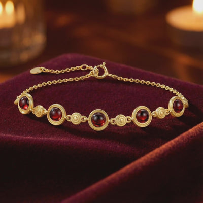 The Calyssa solid gold station bracelet featuring precision-cut simulated garnets.
