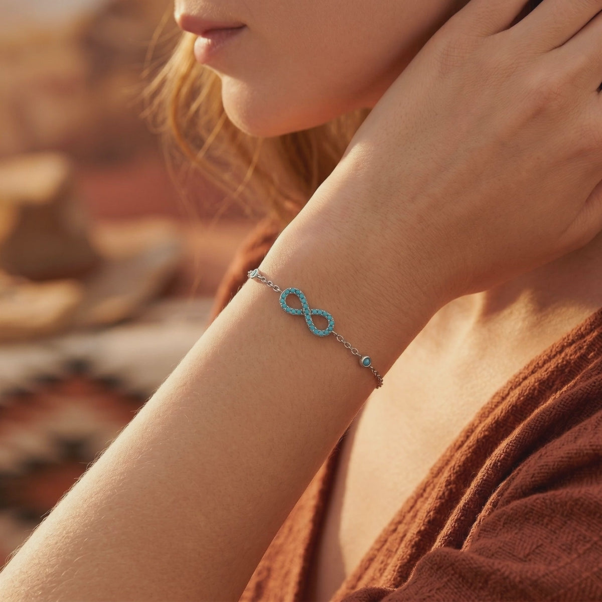 Silver turquoise infinity bracelet with beaded accents shown on a woman's wrist