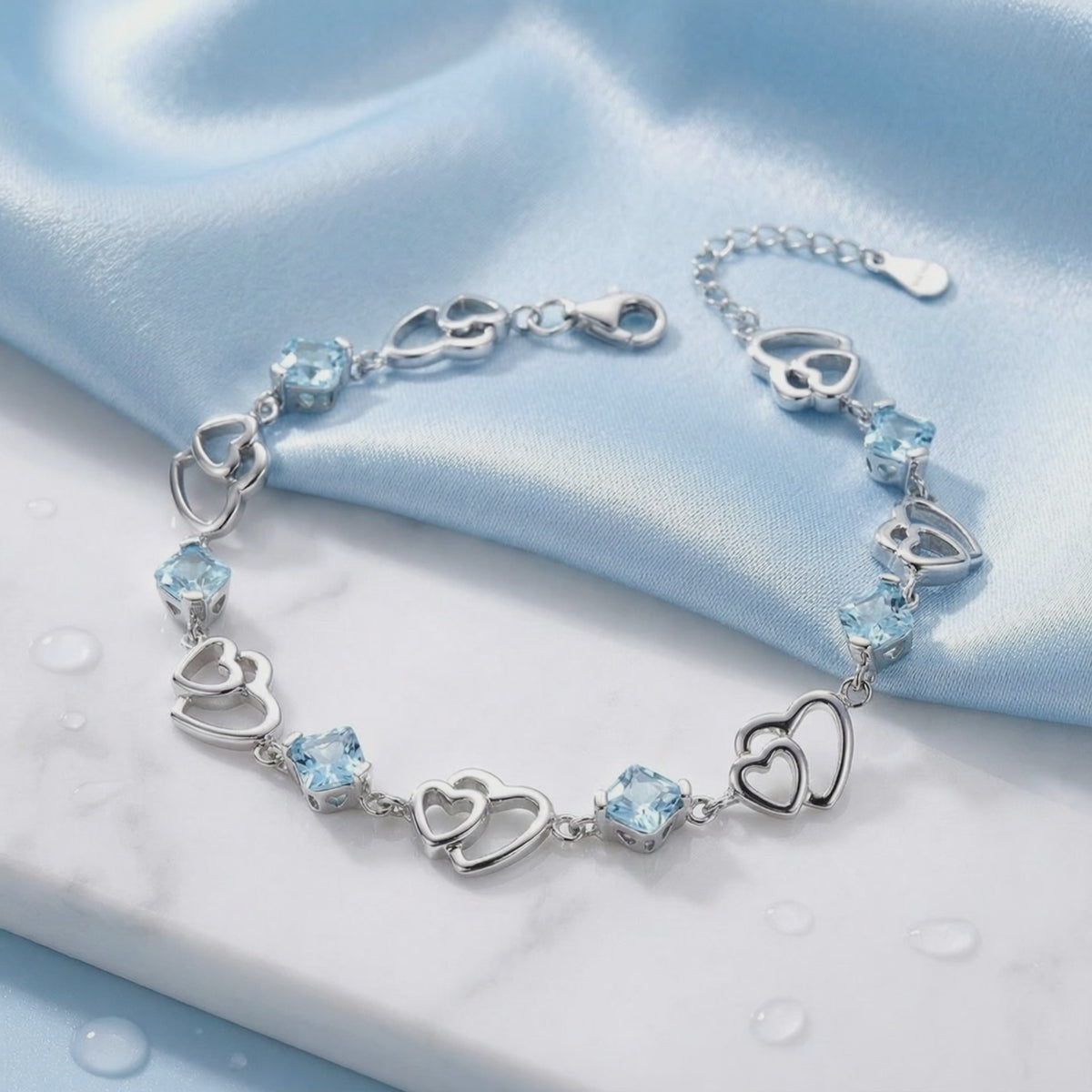 Detailed view of The Caelia Heart solid gold bracelet showcasing its light blue simulated aquamarine stones.