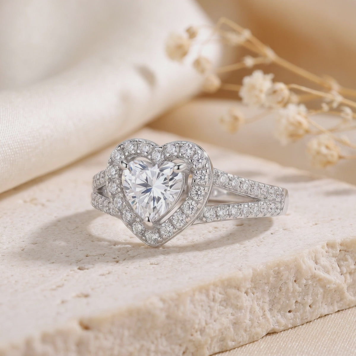 Macro view of a silver heart halo ring with a heart-cut center stone resting on textured stone.