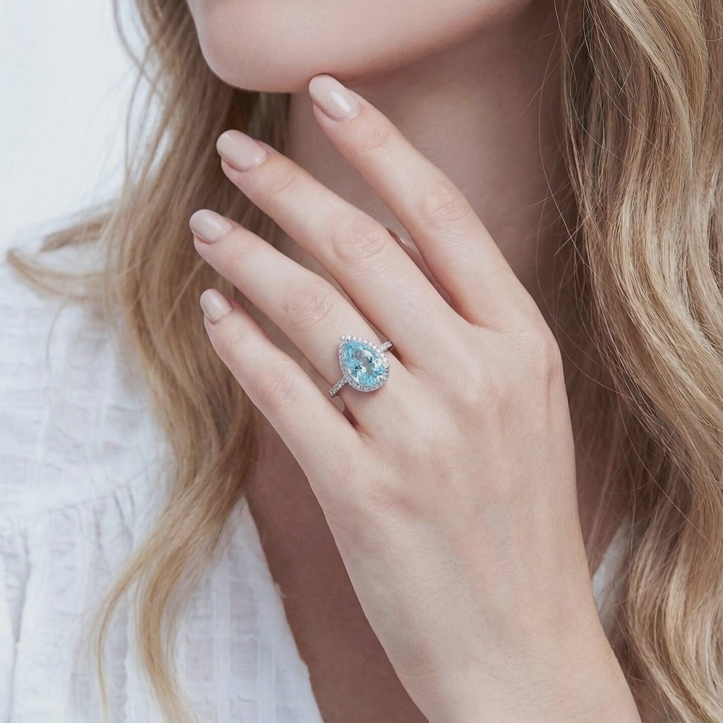 Pear halo simulated aquamarine ring in solid gold.