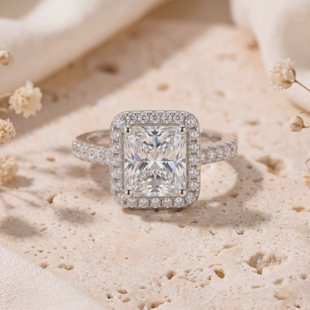 Close-up of a silver halo ring resting upright, showing its rectangular radiant-cut center and pavé setting.