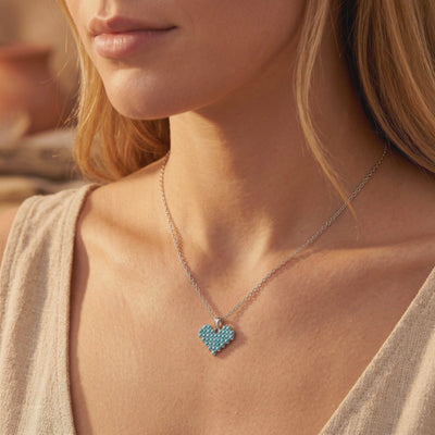Model wearing a silver chain necklace with a heart pendant made of small blue turquoise stones.