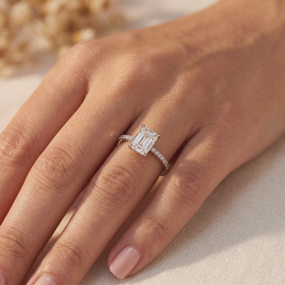 Emerald-cut simulated diamond ring with a pavé band worn on a hand.