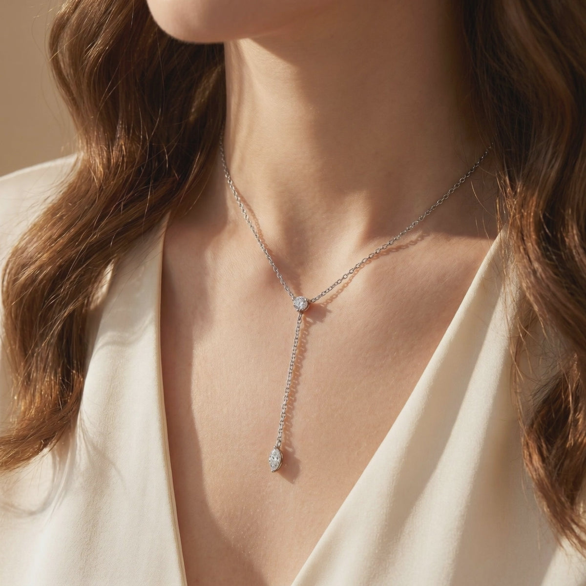 Silver-tone moissanite lariat necklace with a round stone at the junction and a dangling marquise drop, worn on a model.