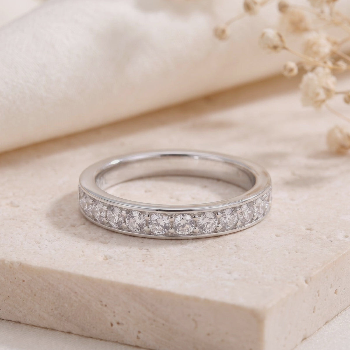 Close-up of the silver eternity ring with channel-set cubic zirconia on a light stone surface.