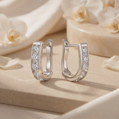 Pair of silver huggie hoop earrings with five channel-set round clear stones on each front curve, displayed upright.
