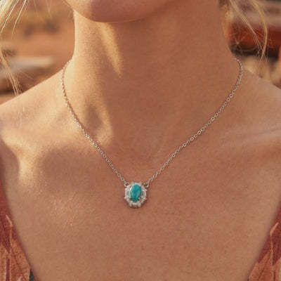 Silver chain necklace with an oval turquoise pendant in a starburst bezel, worn on a model.