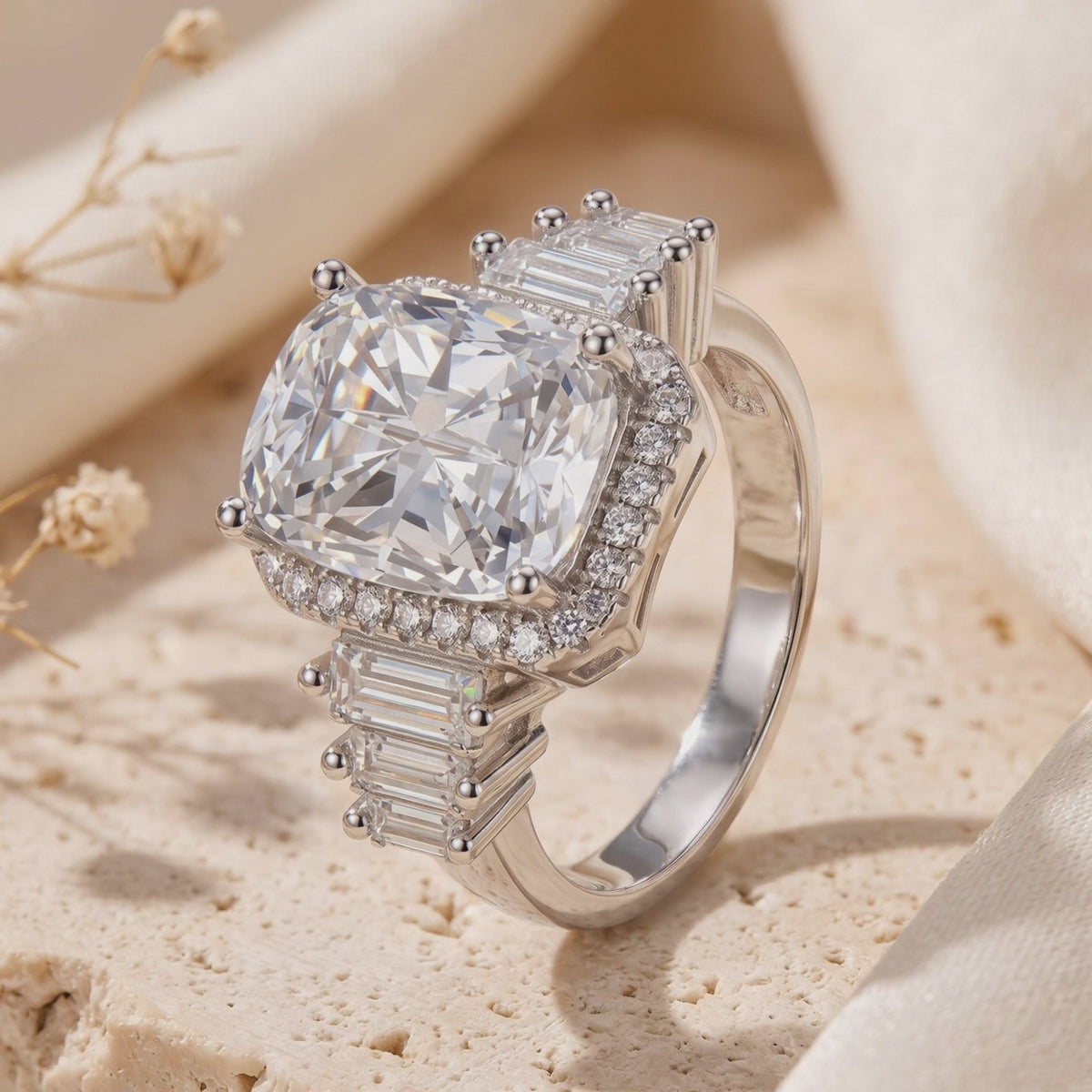 Angled close-up of a silver cushion halo ring with baguette side stones on a beige textured surface
