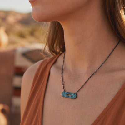 Close-up of a woman wearing the turquoise-studded silver bar necklace with a central star-shaped cutout.