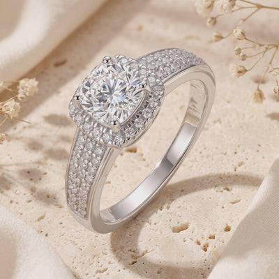 Angled close-up of a silver cushion halo ring with a clear center stone and pavé shoulder