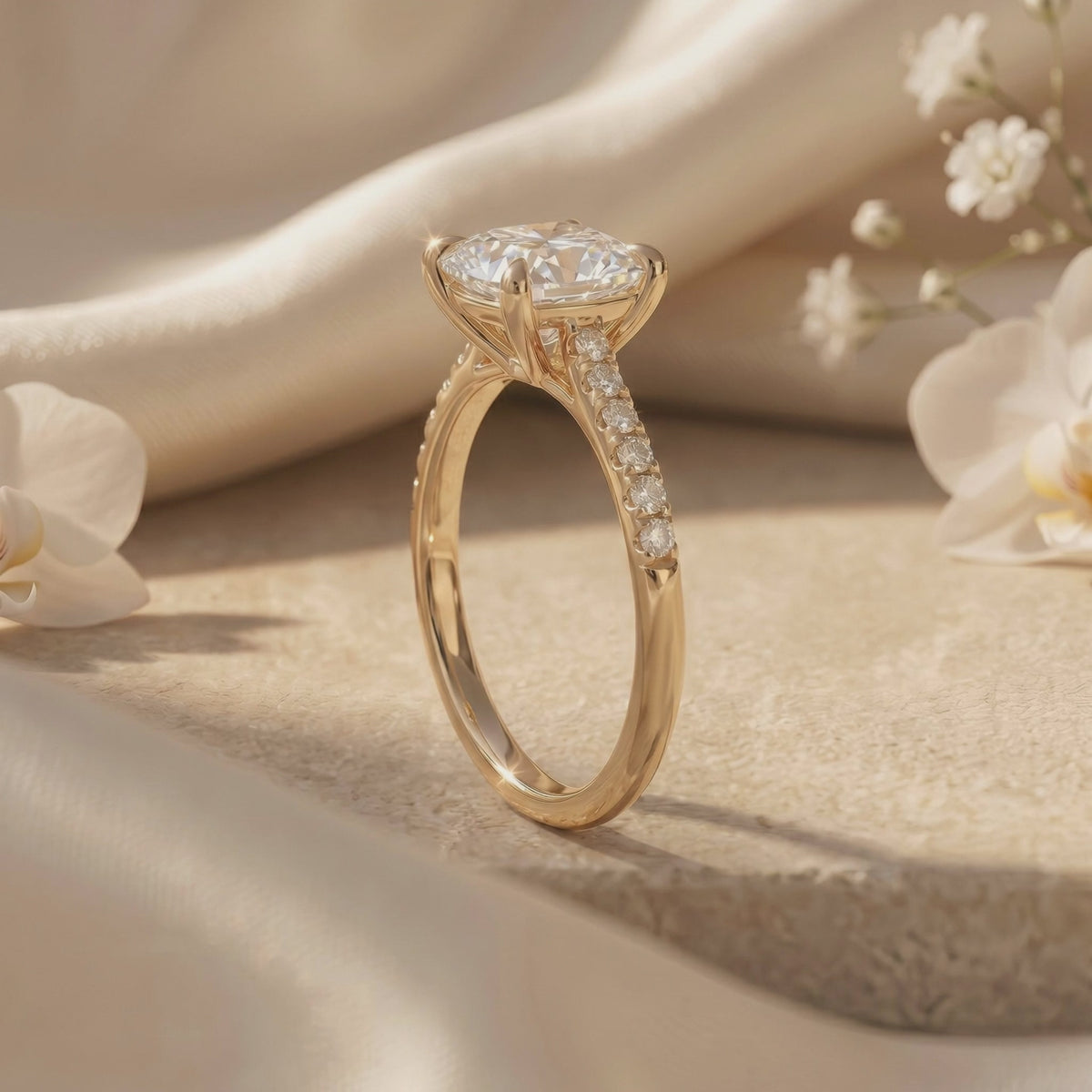Three-quarter side view of an upright cushion-cut solitaire ring, showing its prongs and pavé band.
