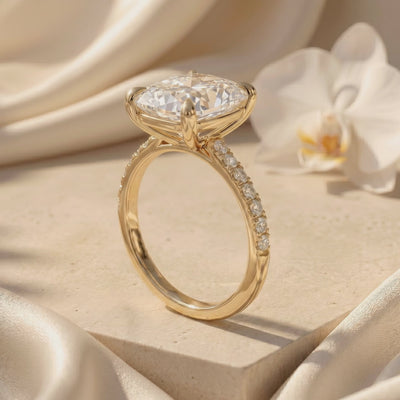 Side profile of a gold-tone cushion rectangular ring with a raised prong setting and pavé stones along the shoulders.