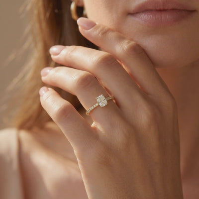 Close-up of a hand wearing a cushion rectangular-cut pavé solitaire ring near the face.