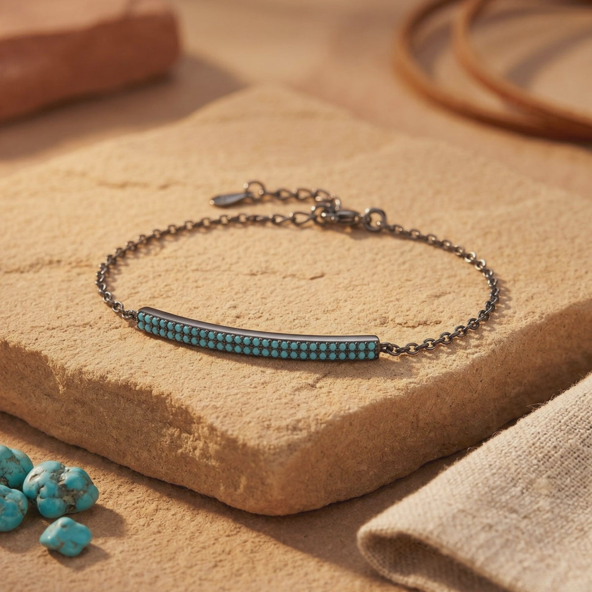 Dark silver chain bracelet with a double-row turquoise bar displayed on a tan stone slab.