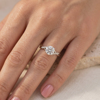 The round moissanite ring with a pavé twist band worn on a hand against a soft neutral background.