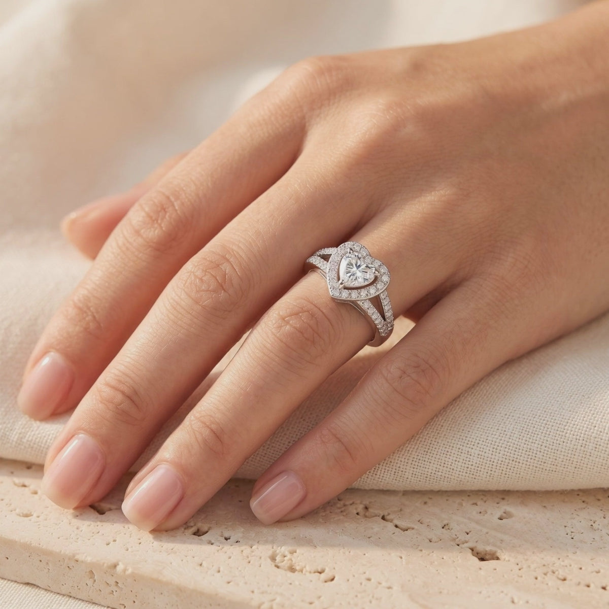 Silver heart halo ring with a heart-cut center stone and split pavé band, worn on a hand.