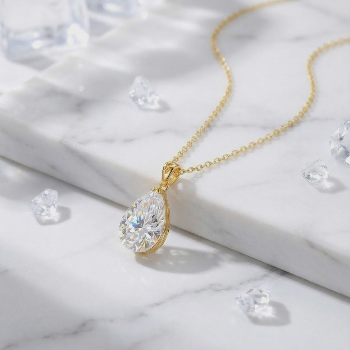 A solid gold necklace with a pear-cut A5 Zirconia pendant displayed on white marble among loose clear crystals.