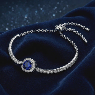 A solid gold bracelet with a simulated sapphire.