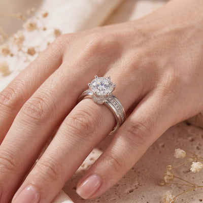 Round solitaire ring with a silver split band and accent stones, shown worn on a hand.