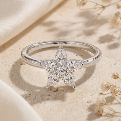 Close-up of a silver ring showing five clear pear-cut stones around a round center stone.