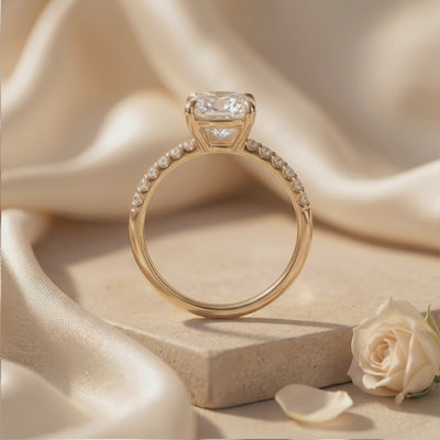Rear view of the cushion-cut pavé solitaire ring standing upright on a beige stone slab.