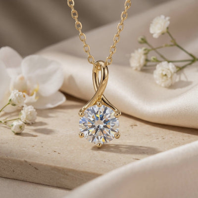 The Lylianne moissanite pendant necklace in solid gold with a twisted loop pendant and round clear stone displayed among white flowers.