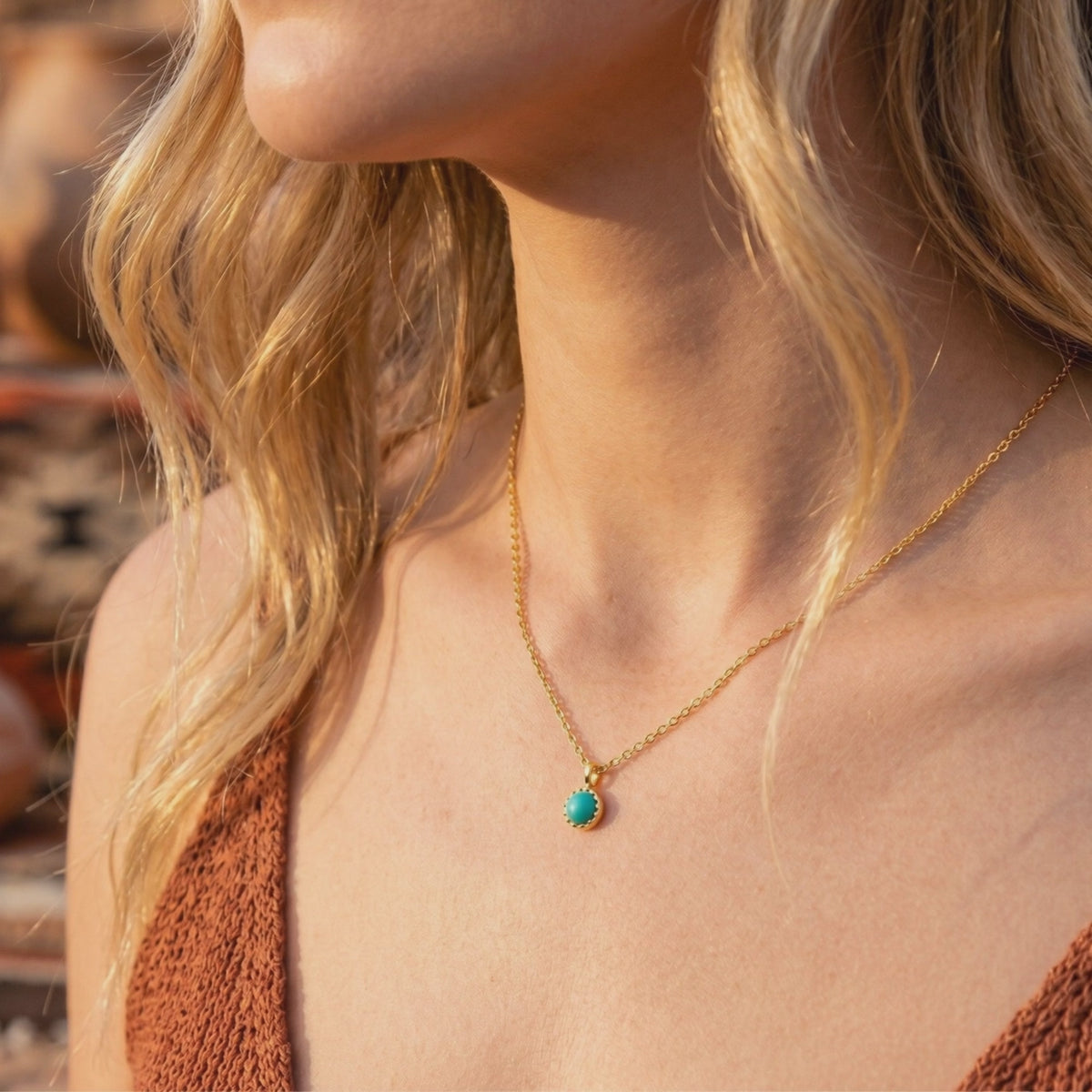 Model wearing a gold chain necklace with a round turquoise pendant in a scalloped bezel.