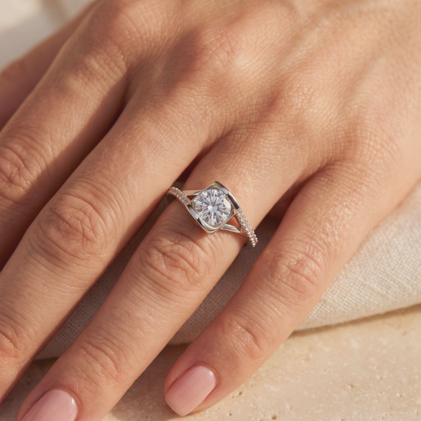 Close-up of a silver-tone bypass ring with a round clear center stone and pavé accents, worn on a hand.