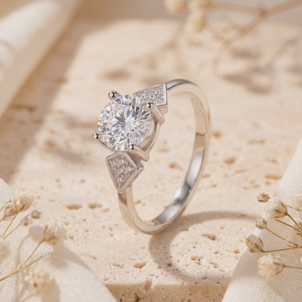 Close-up of the silver Trinity Ring standing on a beige textured surface, showing its round center stone and pavé triangles.