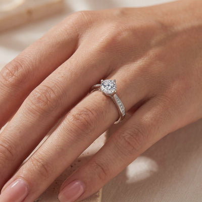 Micro-pavé solitaire ring worn on a finger, with a round clear center stone in a prong setting.