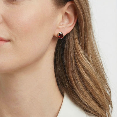 Solid gold huggie earrings with simulated garnet.