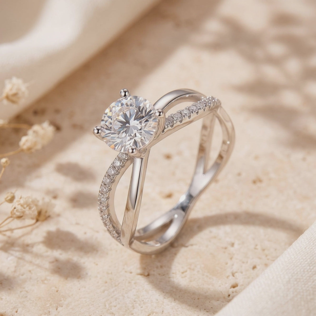 Close-up of the silver crisscross solitaire ring with a round clear center stone on a beige surface.