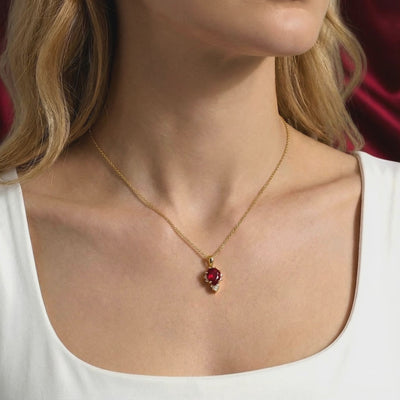 A solid gold necklace with a pear cut simulated ruby.