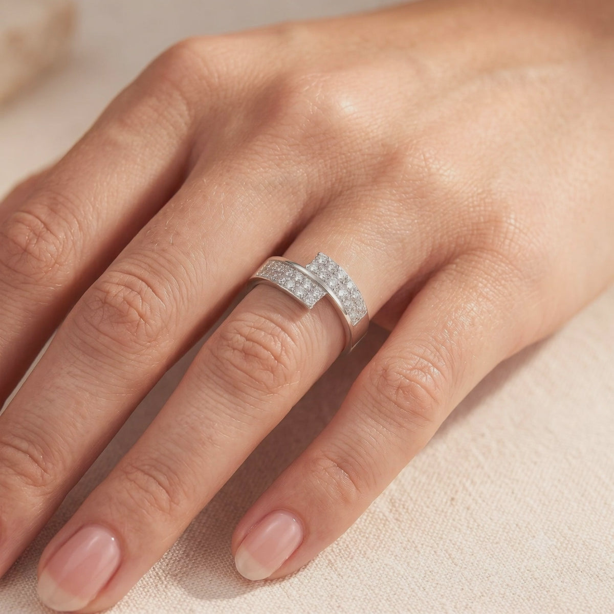 Silver bypass ring with rows of pavé clear stones worn on a hand.