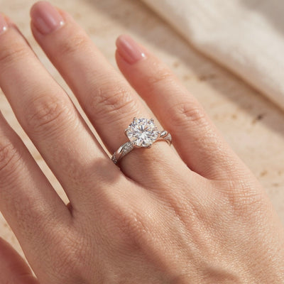 Round solitaire ring with a twisted pavé band worn on a hand.
