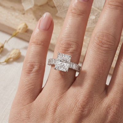 The silver Ismerie ring worn on a finger, with a radiant-cut simulated diamond and baguette-shaped side accents.