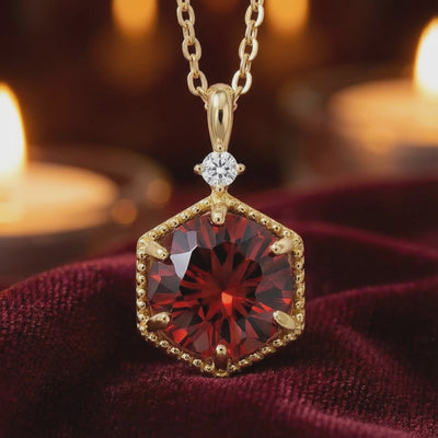 A solid gold necklace with a simulated garnet pendant.